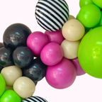 Colorful balloon arch with black, white, pink, green, and beige balloons on a white background