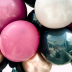 Close-up of pink, white, and black balloons with reflections on a metallic surface.